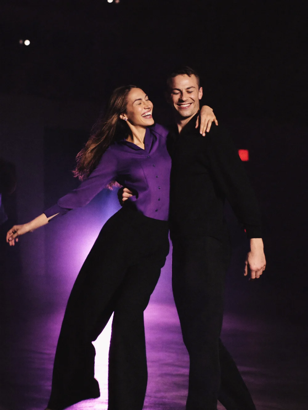 Dançarinos em movimento em estúdio de dança com luzes violeta