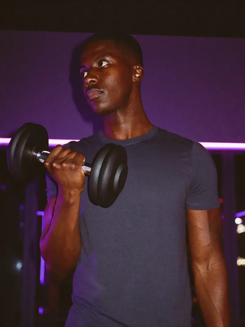 Homem treinando com halter em uma academia.