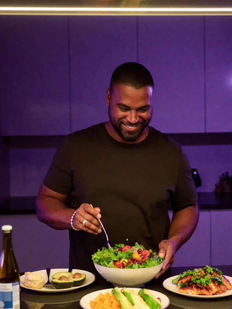 Homem montando uma salada na cozinha.